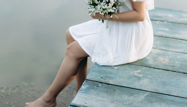 Portrait of beautiful woman on a wooden bridge by the lake at sunny day