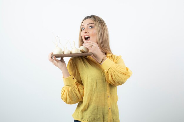 Photo portrait of beautiful woman in yellow blouse holding plate of white turnip