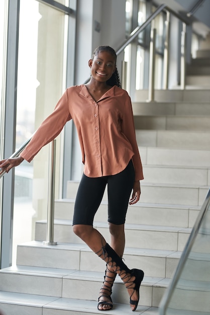 Portrait of a beautiful young African American woman standing against stairs in a building