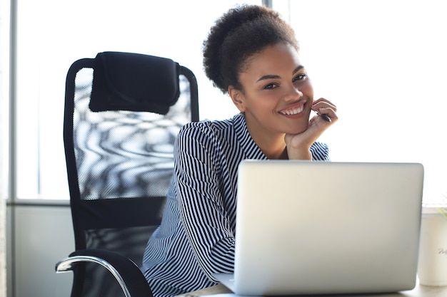 Portrait of beautiful young african american woman working with laptop while sitting at the table.