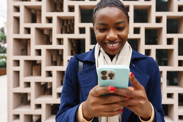 Портрет красивой молодой африканской женщины, использующей свой мобильный телефон на улице
