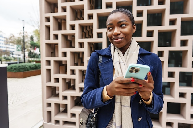 portrait of beautiful young african woman using her mobile phone in the street
