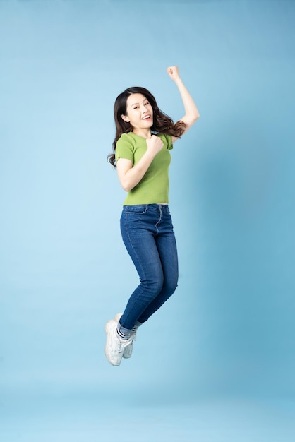 Portrait of beautiful young asian girl jumping up, isolated on blue background