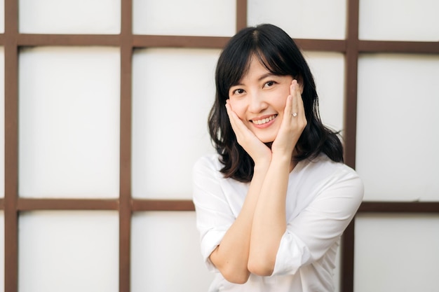 Портрет красивая молодая азиатская женщина счастье сидит на деревянной стене сетки Счастливая женщина улыбается на стене деревянной сетки оздоровительные люди концепции