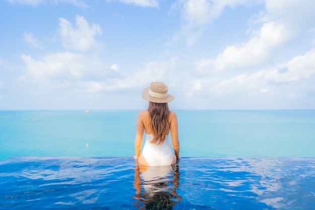 Portrait beautiful young asian woman relax smile leisure around outdoor swimming pool with sea ocean in travel vacation