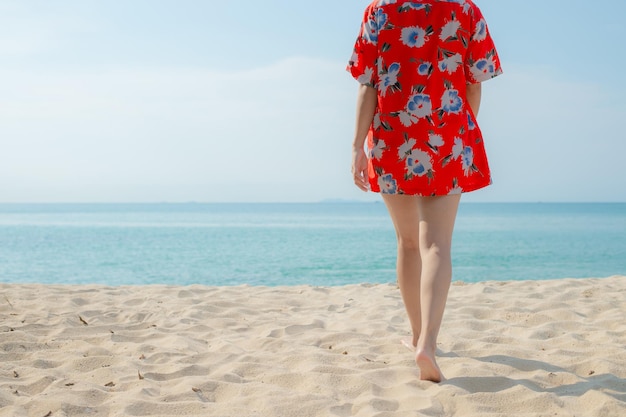 La bella giovane donna asiatica del ritratto si rilassa il tempo libero a piedi intorno all'oceano della spiaggia del mare con la nuvola bianca sul cielo blu nella vacanza di viaggio