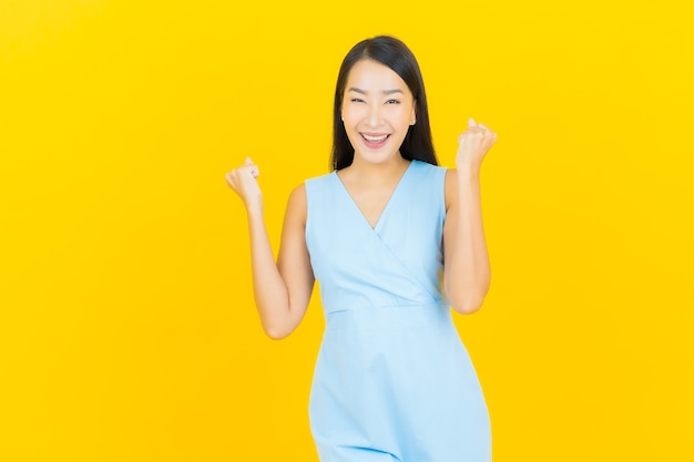 Portrait beautiful young asian woman smile with action on yellow color wall