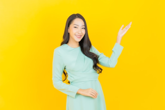 Portrait beautiful young asian woman smile with action on yellow