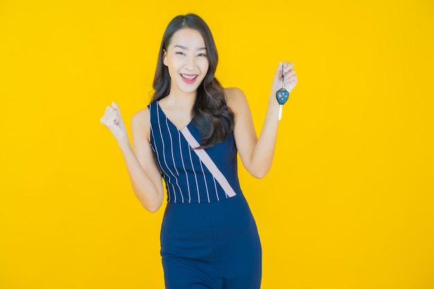 Portrait beautiful young asian woman smile with car key on yellow