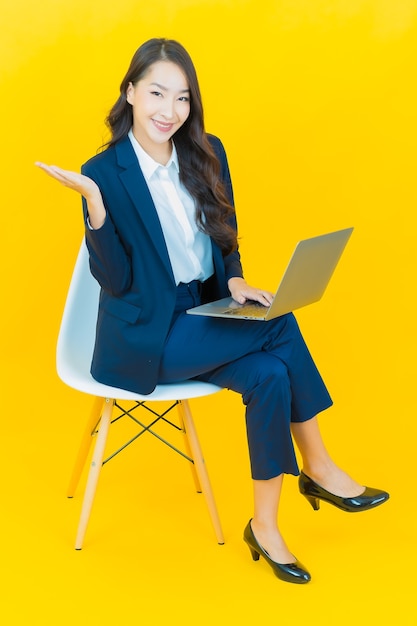 Portrait beautiful young asian woman smile with computer laptop on yellow