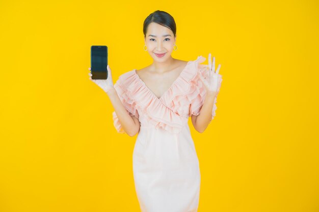 Portrait beautiful young asian woman smile with computer laptop on yellow