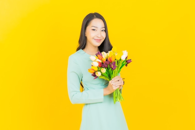 Portrait beautiful young asian woman smile with flower on yellow