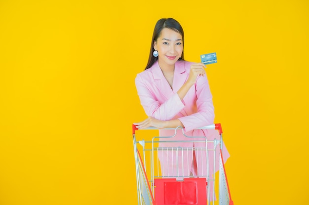 색상 배경에 슈퍼마켓에서 식료품 바구니와 함께 초상화 아름다운 젊은 아시아 여성 미소