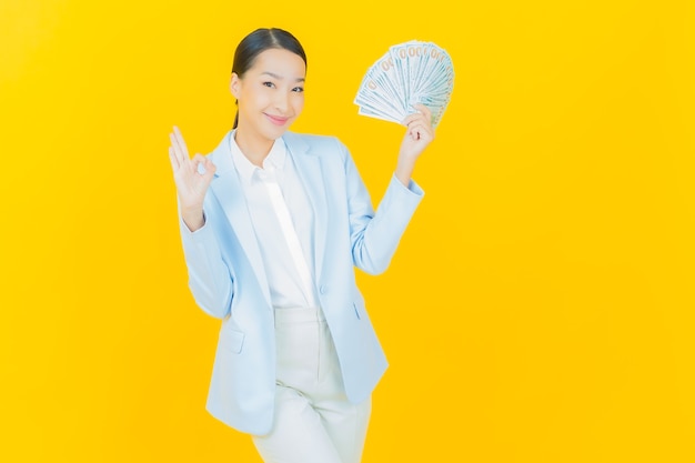 Portrait beautiful young asian woman smile with a lot of cash and money on yellow