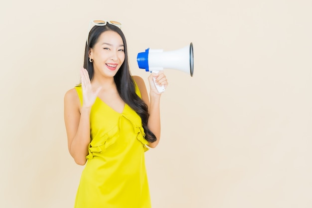 Portrait beautiful young asian woman smile with megaphone on color wall