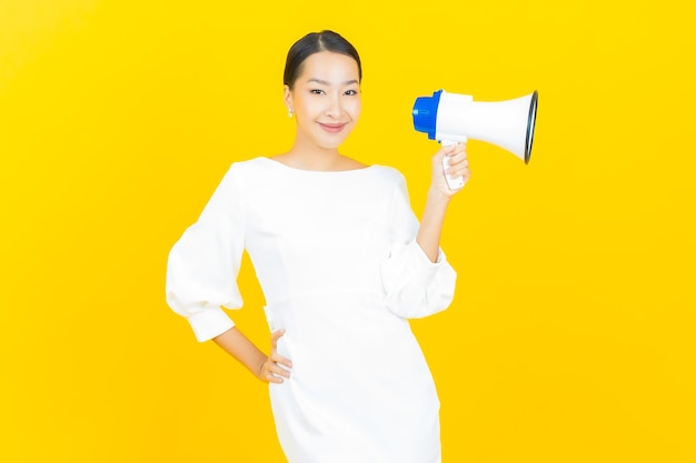 Portrait beautiful young asian woman smile with megaphone on yellow