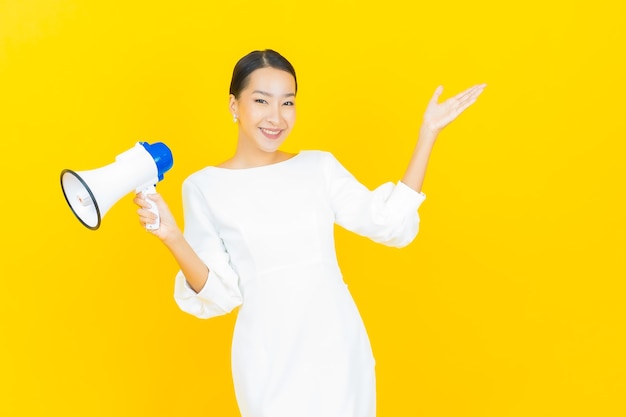 Portrait beautiful young asian woman smile with megaphone on yellow