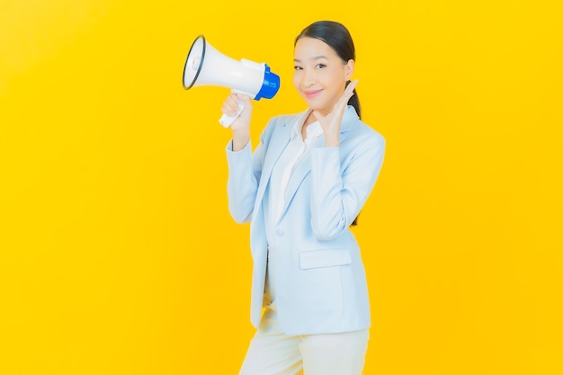 Portrait beautiful young asian woman smile with megaphone on yellow