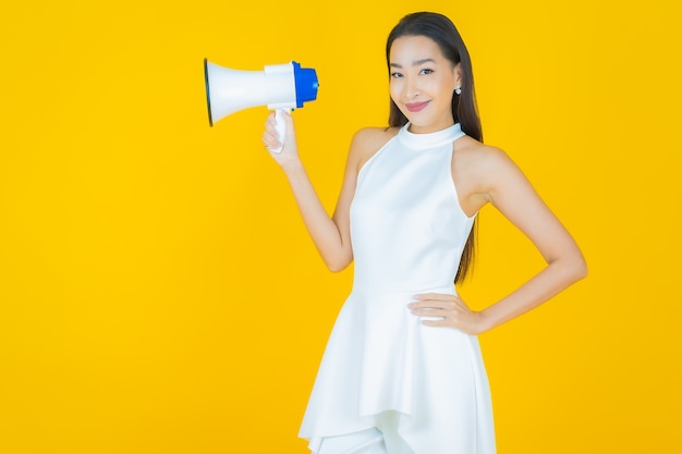 Portrait beautiful young asian woman smile with megaphone on yellow