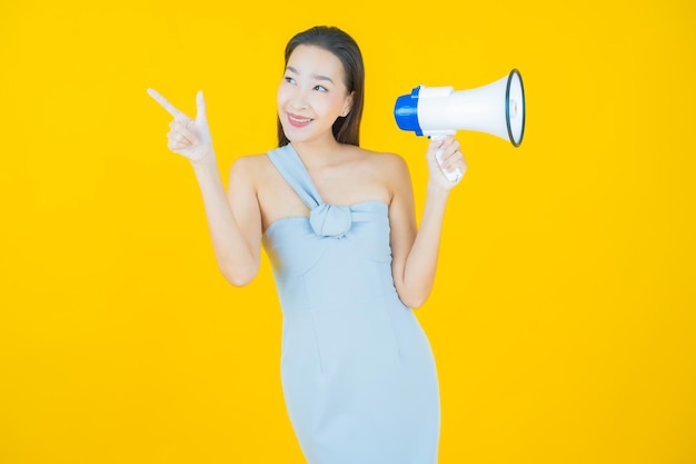 Portrait beautiful young asian woman smile with megaphone on yellow