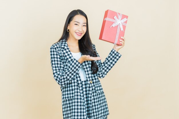 Portrait beautiful young asian woman smile with red gift box on beige