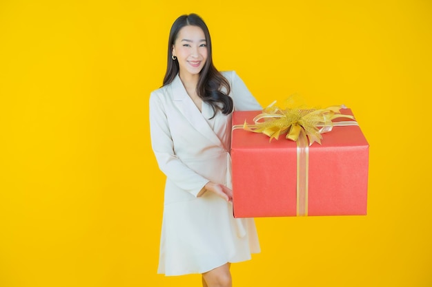 Portrait beautiful young asian woman smile with red gift box on color background