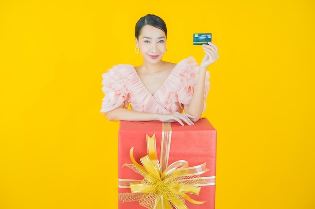 노란색에 빨간색 선물 상자와 함께 초상화 아름 다운 젊은 아시아 여자 미소