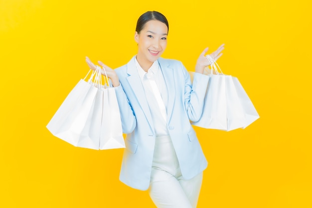Portrait beautiful young asian woman smile with shopping bag on yellow