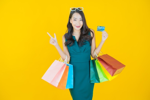 Portrait beautiful young asian woman smile with shopping bag on yellow