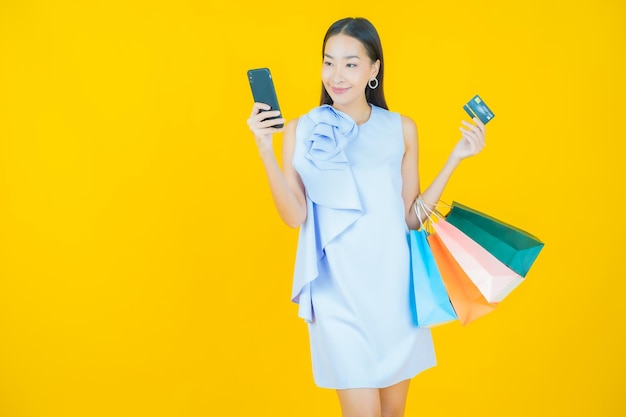 Portrait beautiful young asian woman smile with shopping bag on yellow