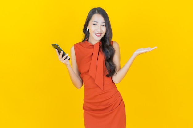 노란색 에 스마트 드폰 을 들고 미소 짓는 아름다운 젊은 아시아 여성 의 초상화