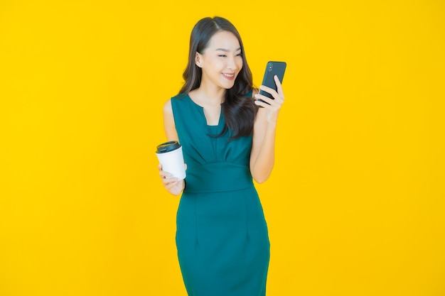 Portrait beautiful young asian woman smile with smart mobile phone on yellow