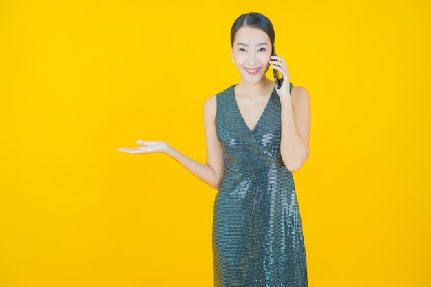 Portrait beautiful young asian woman smile with smart mobile phone on yellow