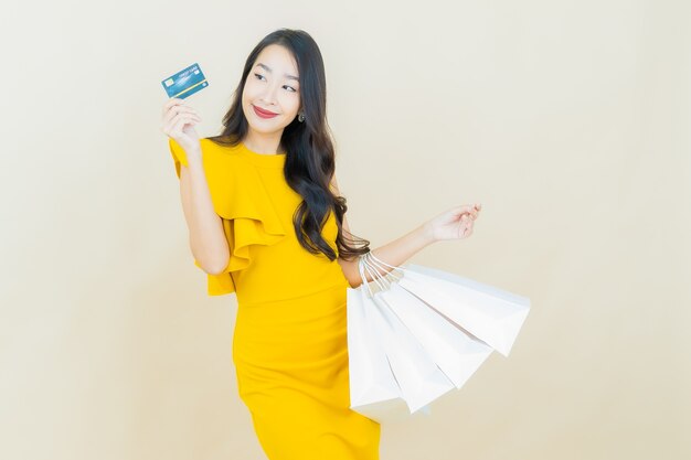 Portrait beautiful young asian woman smiles with shopping bag on beige wall