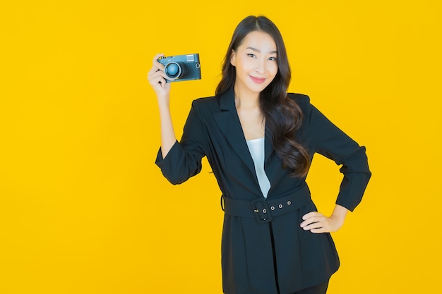 Portrait beautiful young asian woman use camera on yellow