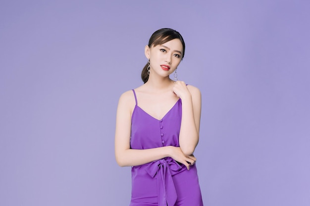 Portrait of beautiful young Asian woman over violet background