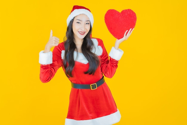 Portrait beautiful young asian woman wear christmas costume with pillow heart on yellow