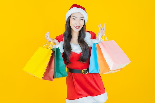 肖像画美しい若いアジアの女性は黄色の買い物袋とクリスマスの衣装を着る