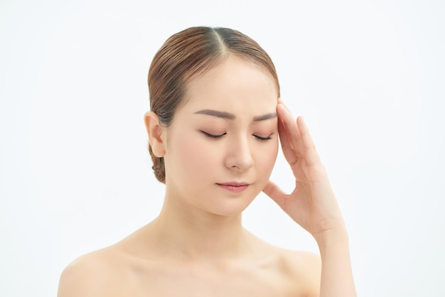Portrait of beautiful young Asian woman with bare shoulders touching her temples feeling stress