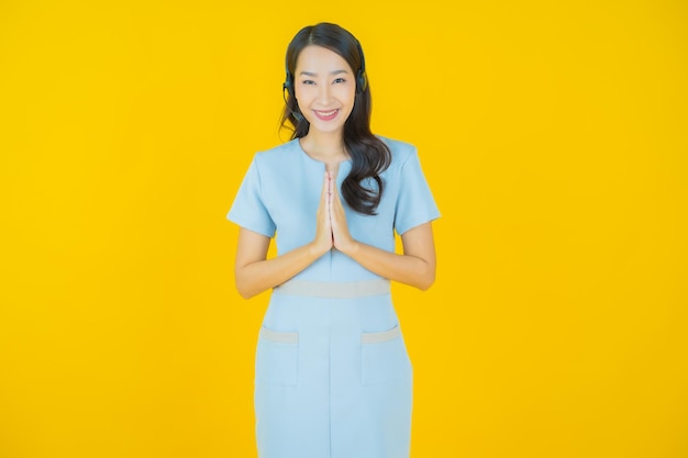 Ritratto bella giovane donna asiatica con call center customer care centro servizi su sfondo di colore giallo