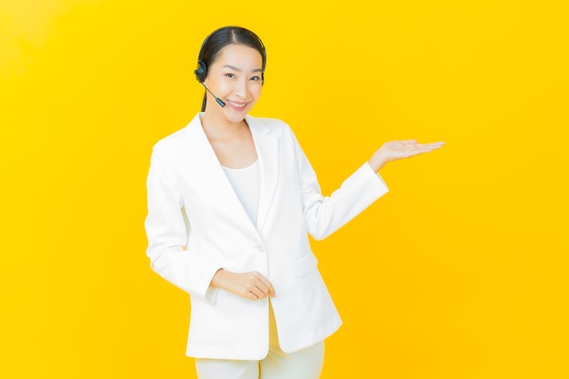 Portrait beautiful young asian woman with call center customer care service center on yellow color wall