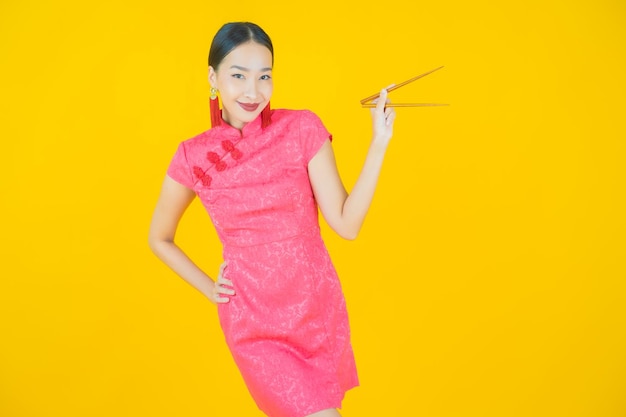 Женщина портрета красивая молодая азиатская с палочками на цветном фоне