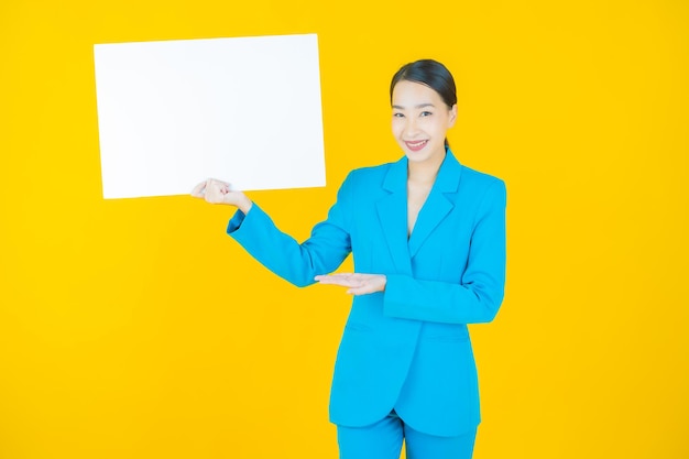 Portrait beautiful young asian woman with empty white billboard on yellow