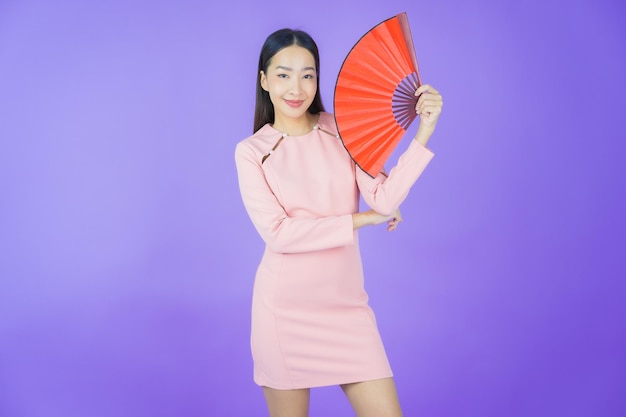 Женщина портрета красивая молодая азиатка с вентилятором на цветном фоне