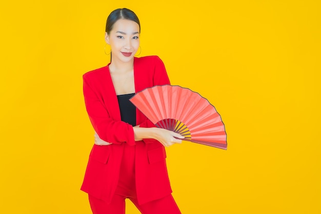 Portrait beautiful young asian woman with fan on yellow