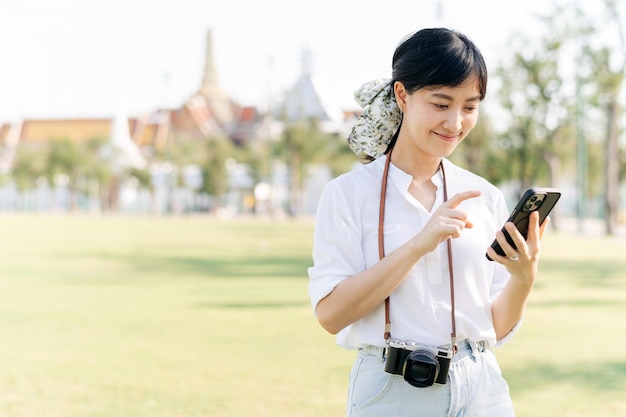 タイのバンコクで壮大な宮殿を背景に夏の休日の休暇旅行にスマート フォンで美しい若いアジア女性の肖像画