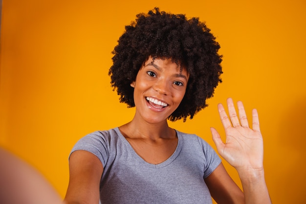 Photo portrait of beautiful young black woman making selfie.