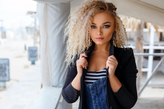 Portrait of a beautiful young blonde woman who poses on camera on the street.