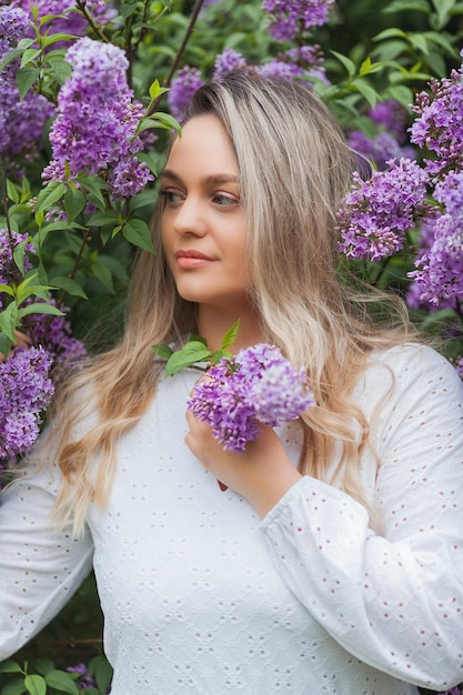 Portrait of beautiful young blueeyed blonde woman near blooming lilac Spring