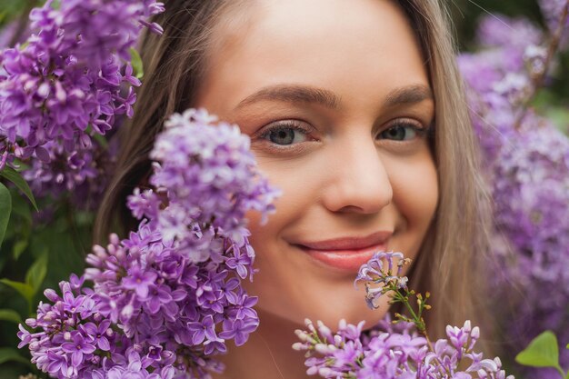 Photo portrait of beautiful young blueeyed blonde woman near blooming lilac spring